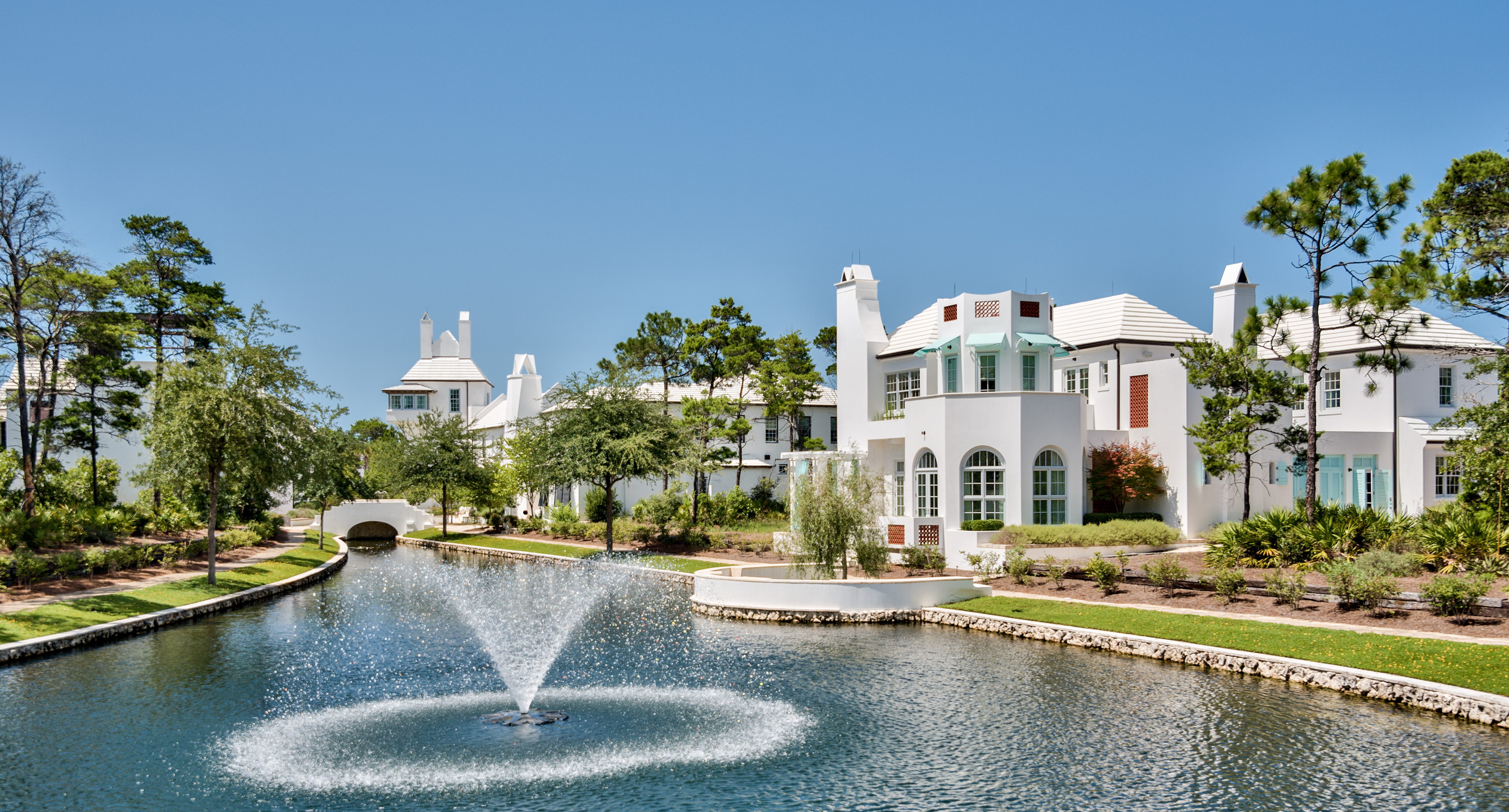 A flowing fountain atop a residential lake with Alys Beach homes in the background